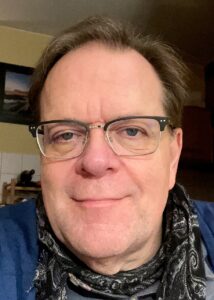 Foto von Matthias Rösch, er trägt eine Brille und ein Halstuch.