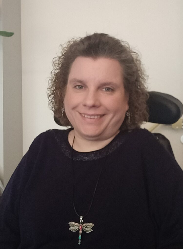 Foto von Sina Rimpo, Sina sitzt im Rollstuhl und trägt ein schwarzes Oberteil.