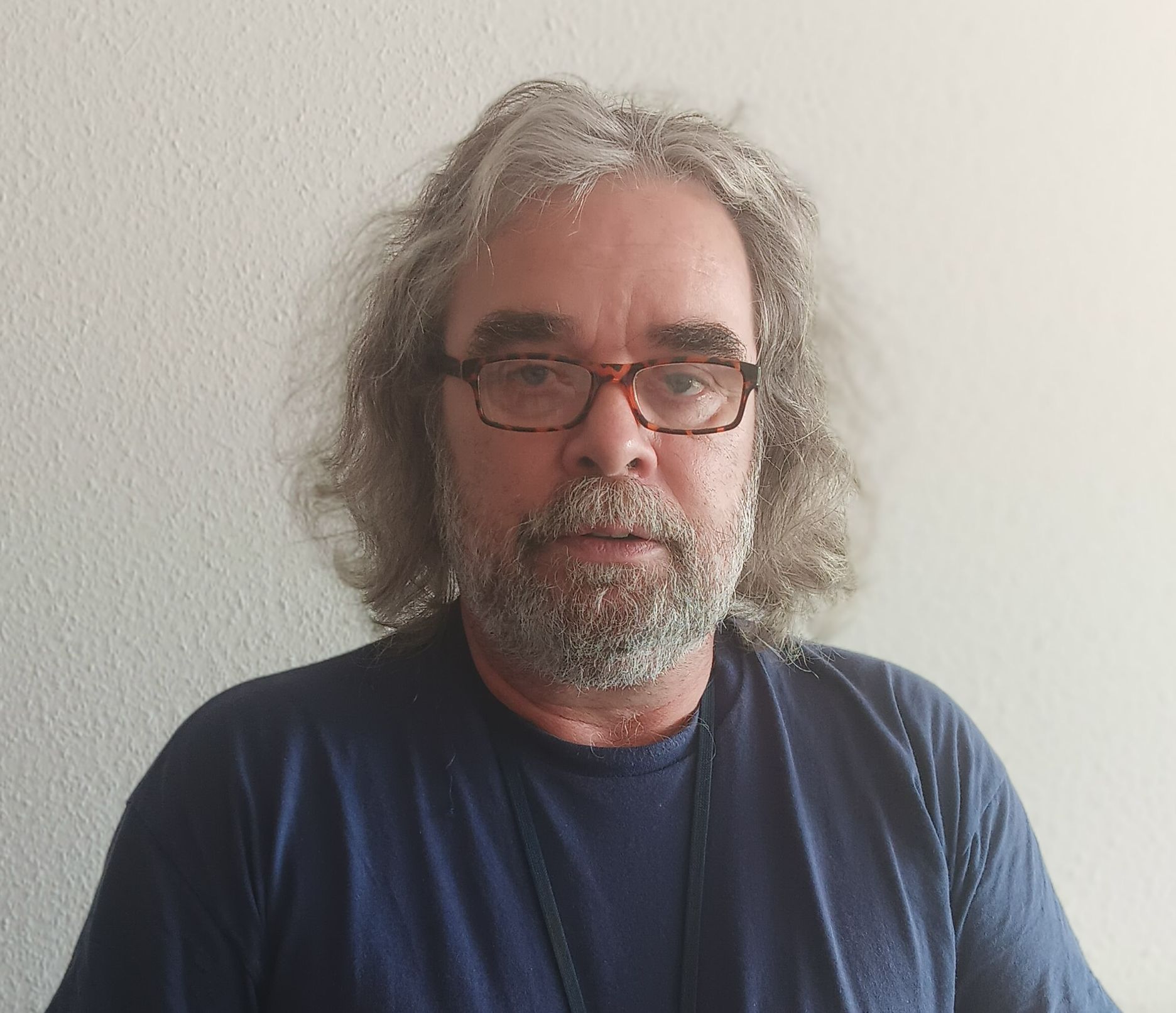 Bild von Thomas Künnecke. Er hat graue Haare, einen Bart und trägt ein dunkelblaues Oberteil.
